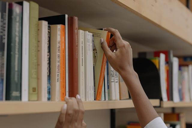 Студент выбирает учебник на полке